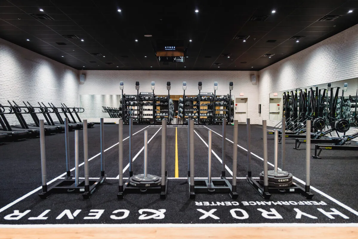 A smiling man in a suit with his arms crossed, standing outdoors.